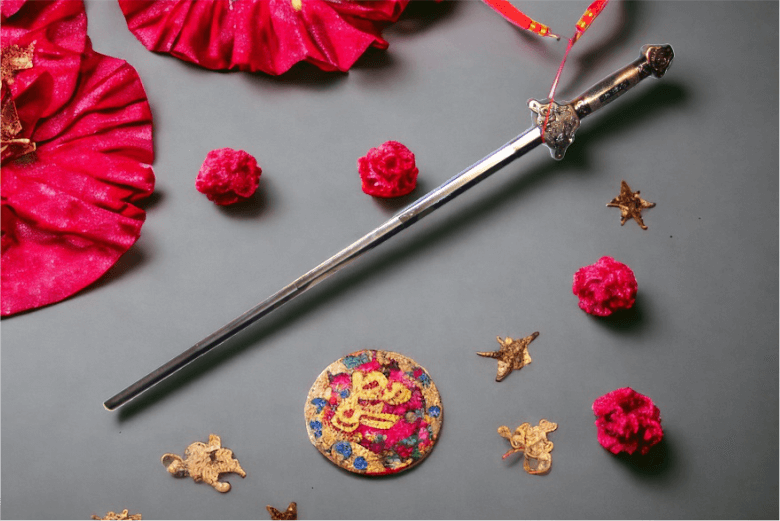 Schwert Jian. Auf dem Bild ist ein ungeschliffenes "Wudang Schwert" zusehen. Es liegt auf einem grauen Hintergrund, verziert mit schönen Asiatischen Knoten, Muster und Stoffelementen.